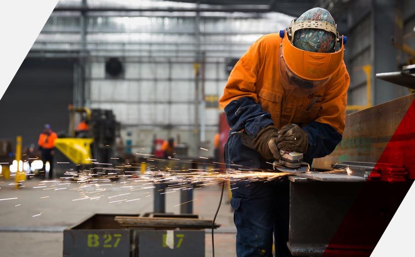 A worker grinds metal.